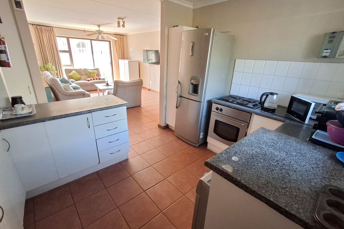 Open-plan kitchen and living area featuring tiled flooring, functional cabinetry, and direct access to the living space.