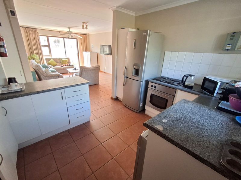 Open-plan kitchen and living area featuring tiled flooring, functional cabinetry, and direct access to the living space.