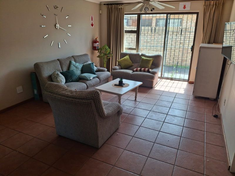 A living room featuring tiled flooring, a ceiling fan, and a sliding glass door providing access to the exterior.