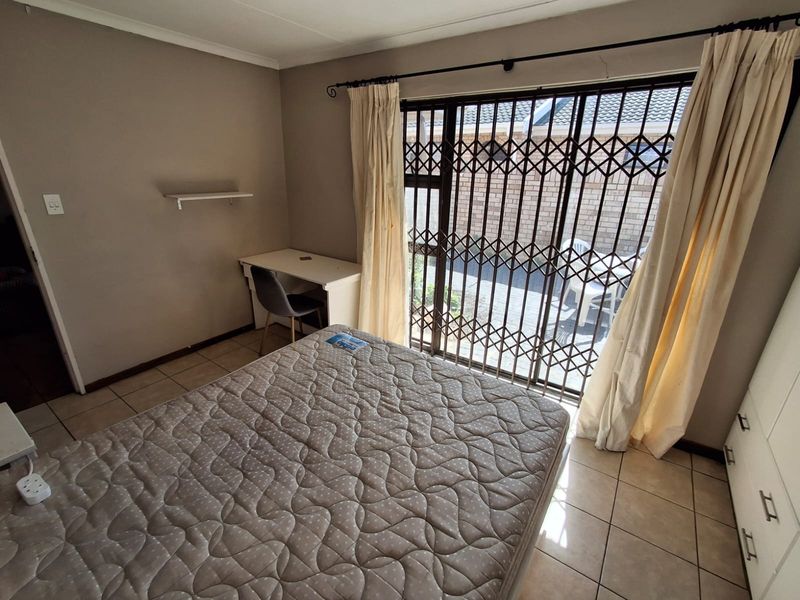 Bedroom featuring tiled flooring, built-in storage, and a sliding glass door with a security gate providing access to the exterior.