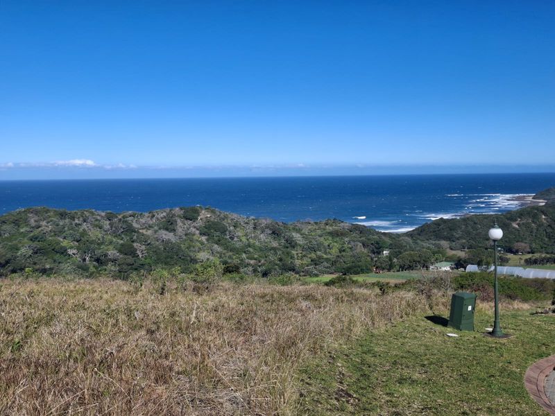 A scenic elevated view overlooking coastal hills and the ocean, featuring a clear horizon and natural landscape.
