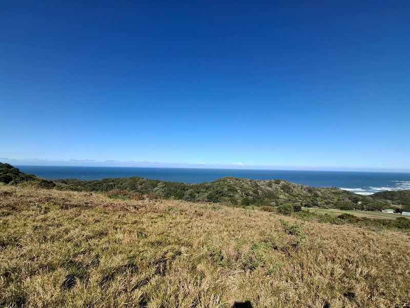 A scenic elevated view overlooking coastal hills and the ocean, showcasing the natural landscape of the vacant residential property.