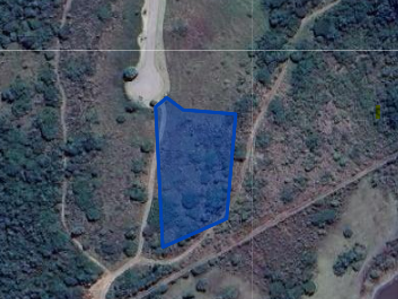 An aerial view of a vacant residential plot of land with access road frontage.