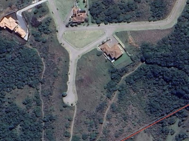 An aerial view of a residential development area featuring paved roads, established homes, and surrounding natural vegetation.