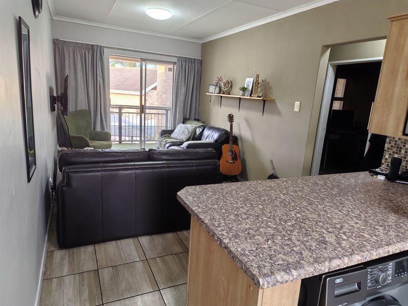 Open plan living area featuring a kitchen island with laminate countertop, tiled flooring, and a sliding glass door leading to a balcony.