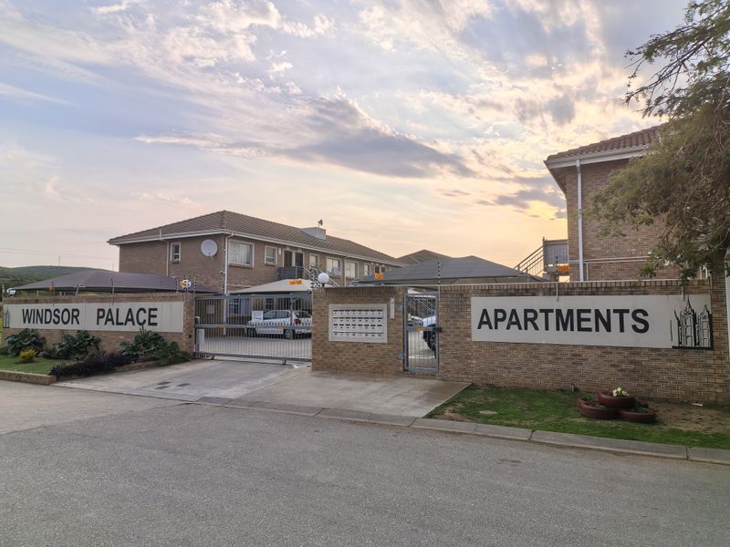 Front entrance view of Windsor Palace Apartments, featuring a brick perimeter wall, secure gated access, and post boxes.