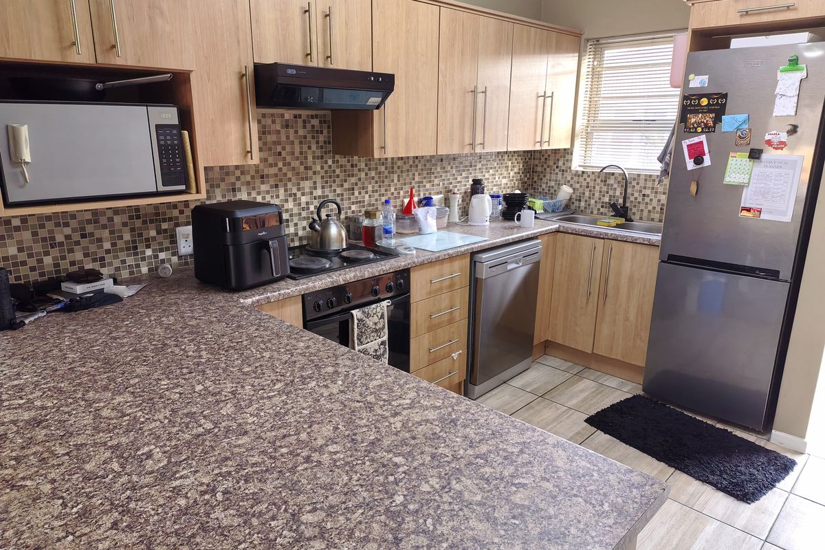 Functional kitchen featuring light wood-tone cabinetry, mosaic tile backsplash, laminate countertops, and integrated appliances, offering a practical layout for daily meal preparation.