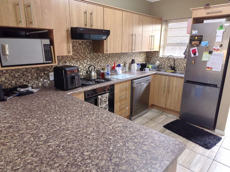 Functional kitchen featuring light wood-tone cabinetry, mosaic tile backsplash, laminate countertops, and integrated appliances, offering a practical layout for daily meal preparation.