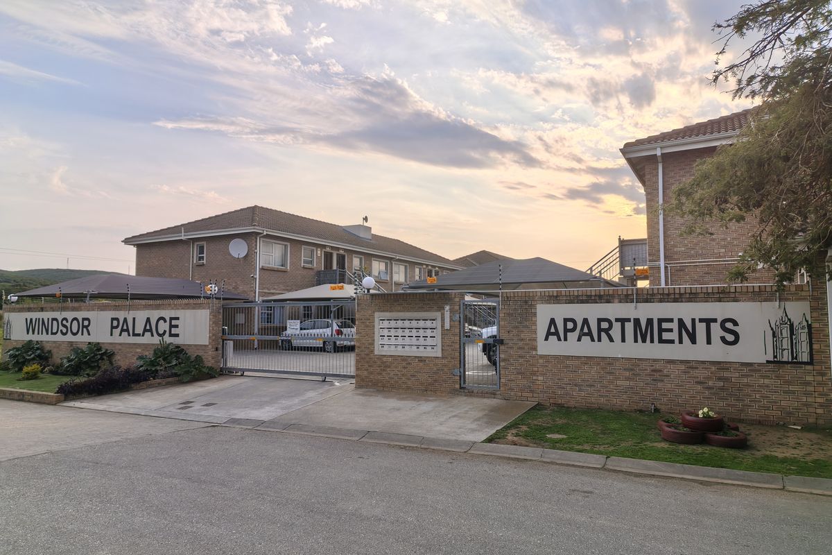 Front entrance view of Windsor Palace Apartments, featuring a brick perimeter wall, secure gated access, and post boxes.