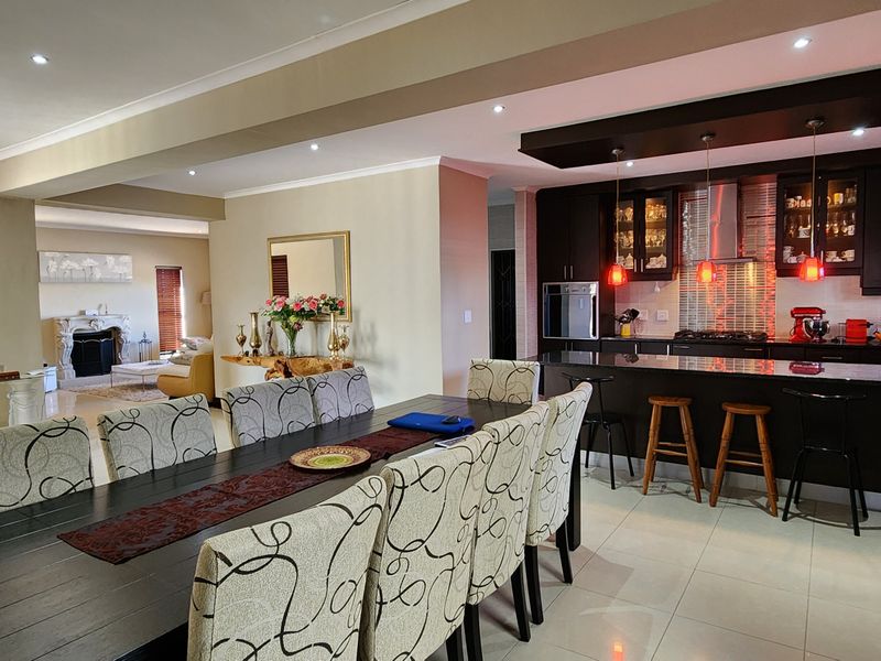 Spacious open-plan living and dining area featuring a modern kitchen with dark cabinetry, granite countertops, and integrated appliances, flowing into the dining space.