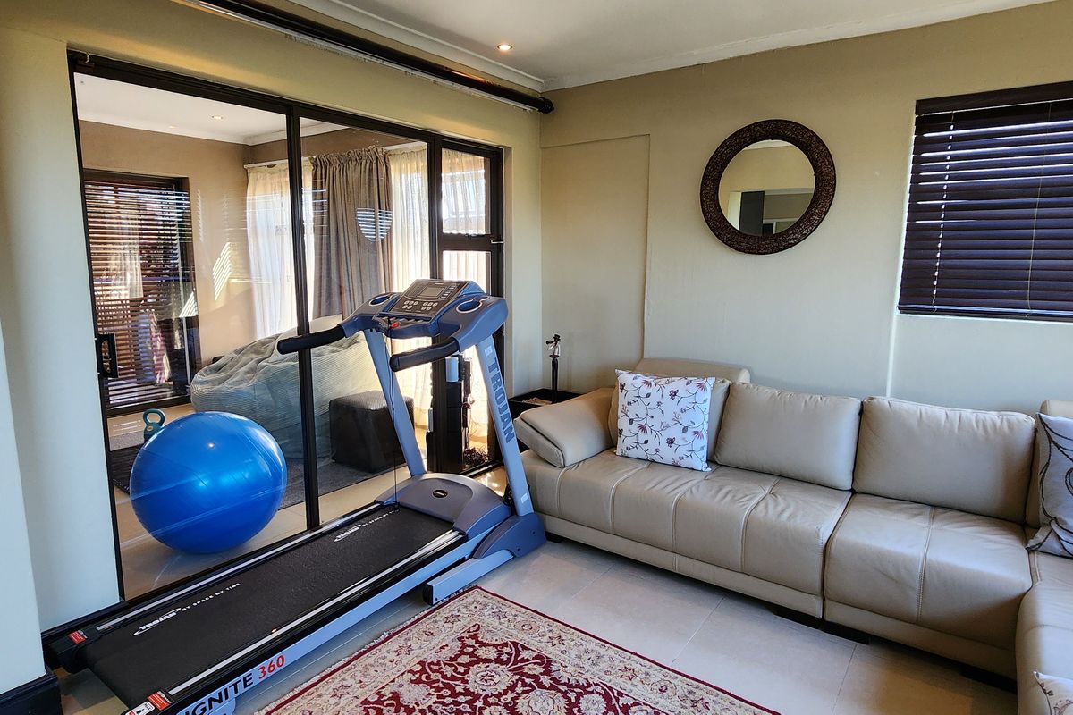 A comfortable living area featuring tiled floors, recessed lighting, and large sliding glass doors that provide access to an adjacent room.