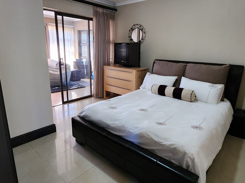 A well-maintained bedroom featuring tiled flooring and a sliding glass door providing access to an adjoining space.