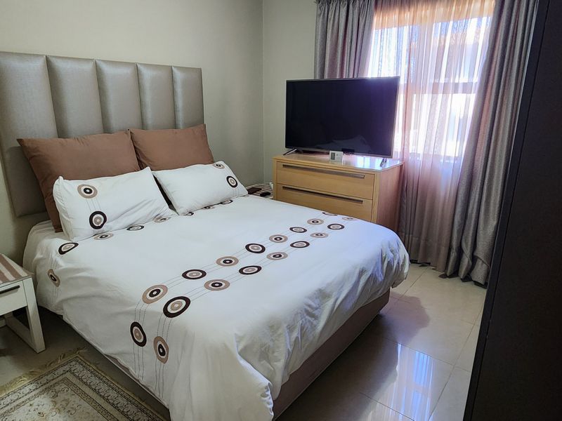 A functional bedroom featuring tiled flooring and neutral wall finishes, providing a comfortable and well-maintained living space.