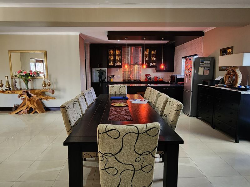 Spacious open-plan living and dining area featuring tiled floors, a modern kitchen with built-in cabinetry, and a recessed ceiling bulkhead.