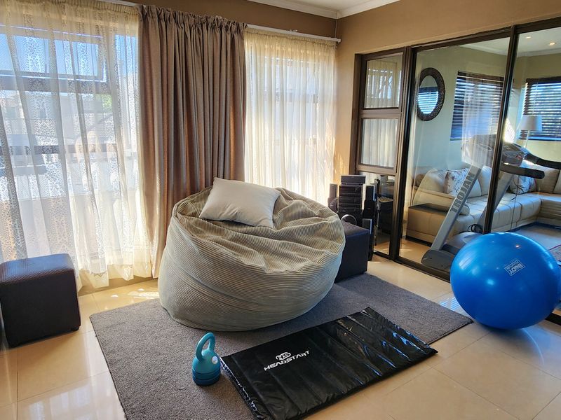 A bright, tiled home gym area featuring large sliding glass doors that provide natural light and a view into the adjacent living space.