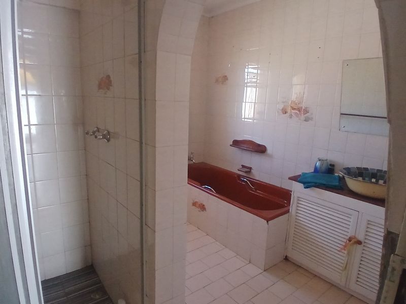 A dated bathroom featuring a separate shower enclosure, a built-in bathtub, and a vanity cabinet with tiled surfaces throughout.