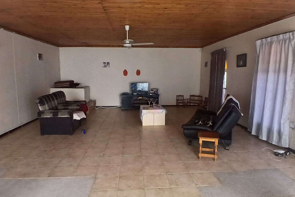 Spacious living area featuring a timber-clad ceiling, ceiling fan, and tiled flooring throughout.