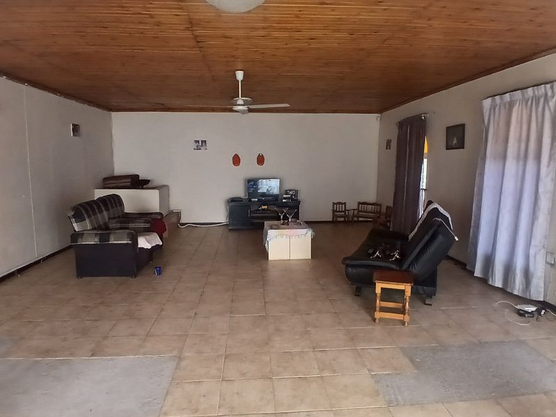 Spacious living area featuring a timber-clad ceiling, ceiling fan, and tiled flooring throughout.