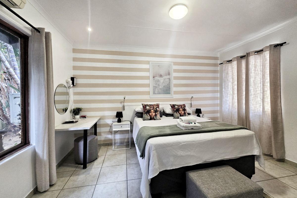 A well-maintained bedroom featuring tiled flooring, a built-in desk, and a wall-mounted air conditioning unit, offering a comfortable and functional living space.