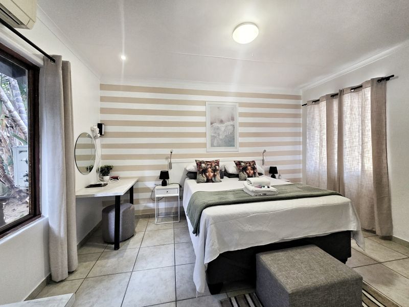 A well-maintained bedroom featuring tiled flooring, a built-in desk, and a wall-mounted air conditioning unit, offering a comfortable and functional living space.