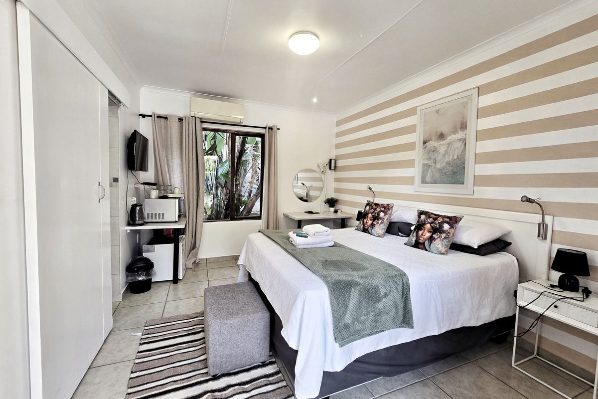 A bedroom featuring tiled flooring, a built-in wardrobe, and a split-system air conditioner, with a window providing natural light.