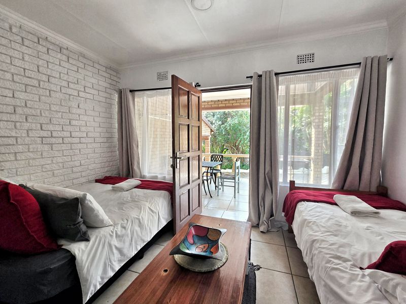 A bedroom featuring an exposed brick wall, tiled flooring, and direct access to an outdoor patio area through a sliding glass door.