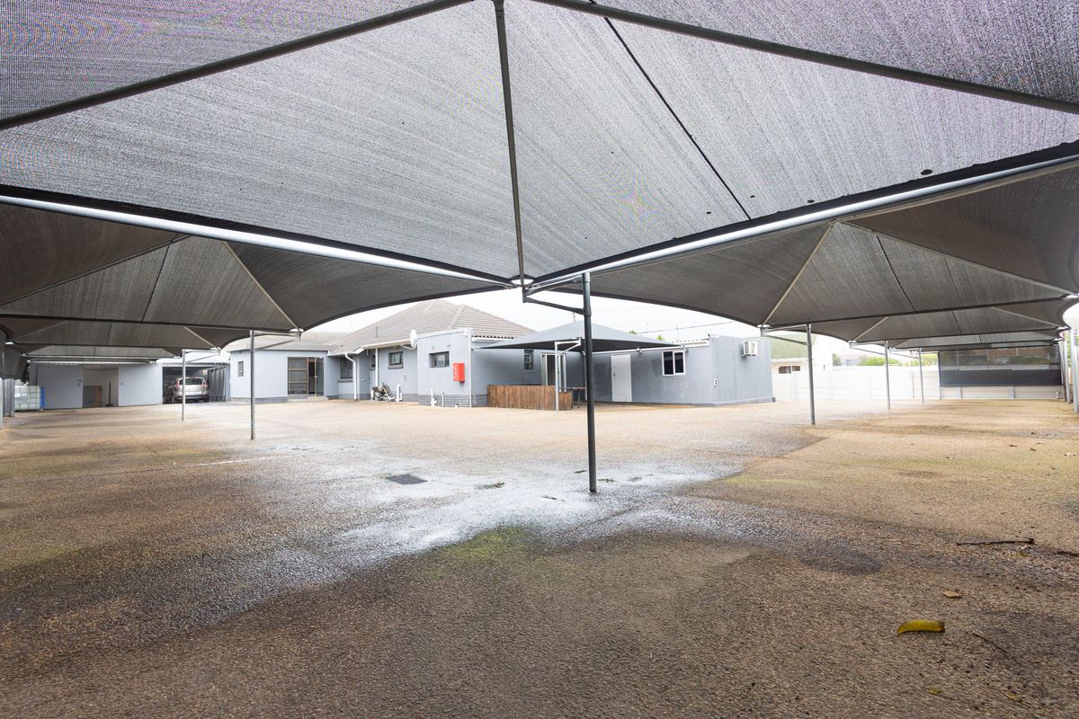 Spacious paved rear courtyard area featuring extensive shade sail coverage, providing a functional outdoor space suitable for parking or multi-purpose use.