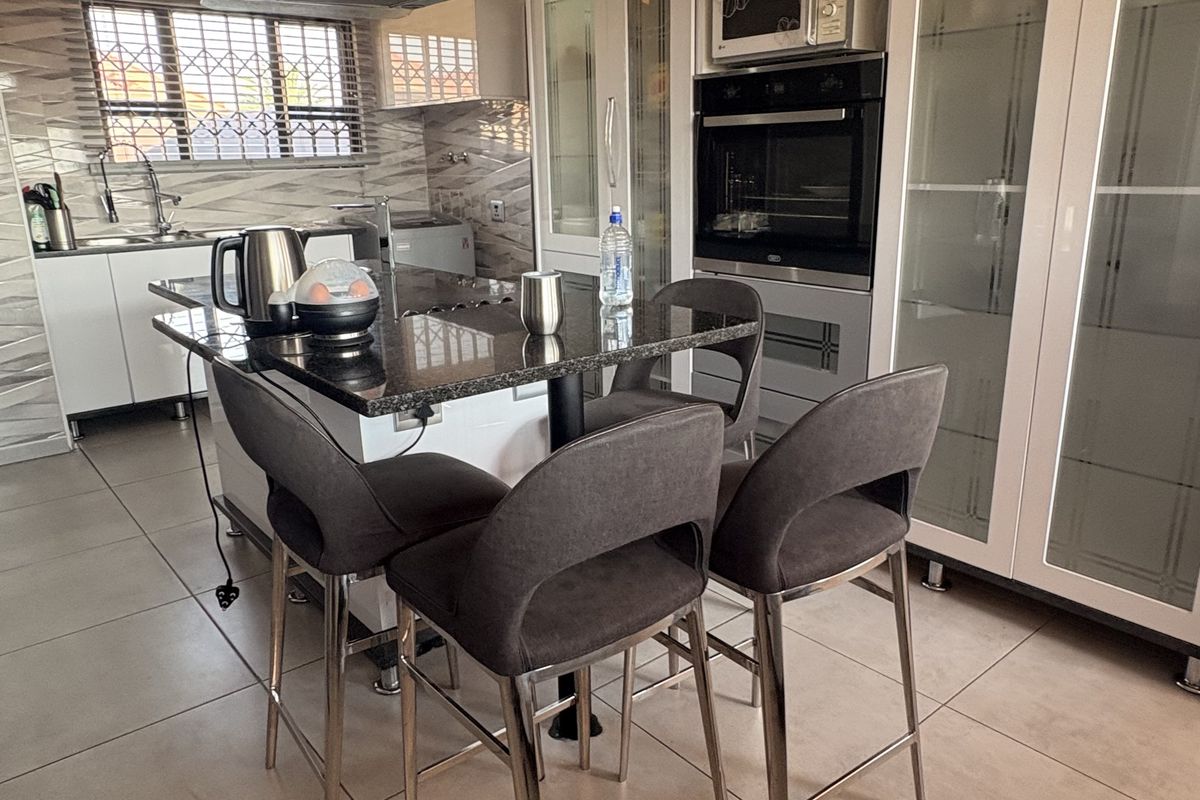 Modern kitchen featuring a central island with granite countertops, built-in oven and microwave, glass-front cabinetry, and tiled flooring.