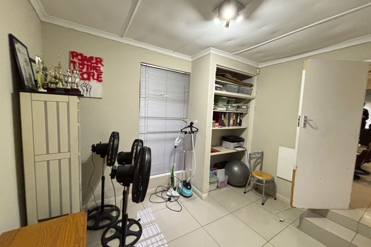 A bedroom featuring tiled flooring, built-in shelving, and venetian blinds. The room requires cosmetic updates to the ceiling and door frame.