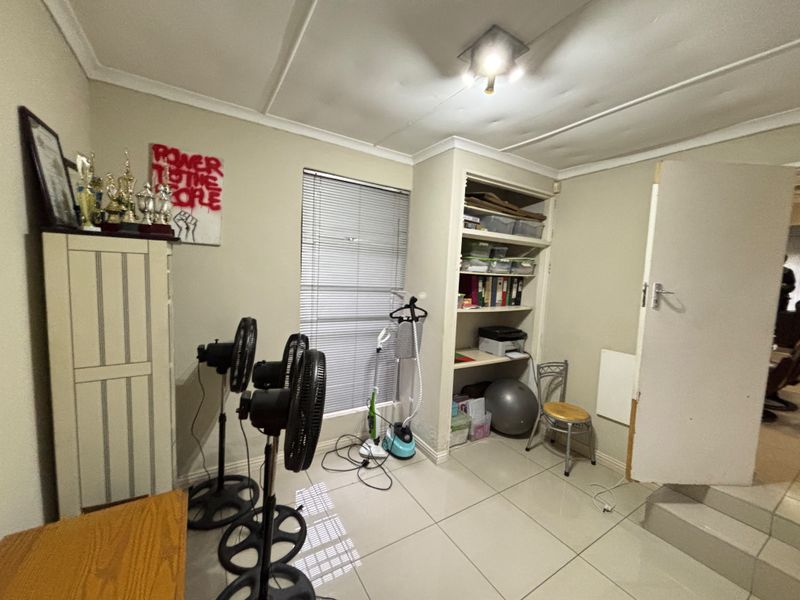 A bedroom featuring tiled flooring, built-in shelving, and venetian blinds. The room requires cosmetic updates to the ceiling and door frame.