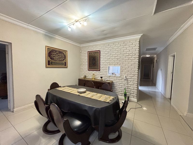 Dining room featuring a white painted exposed brick feature wall, tiled flooring, and coved ceiling with track lighting.