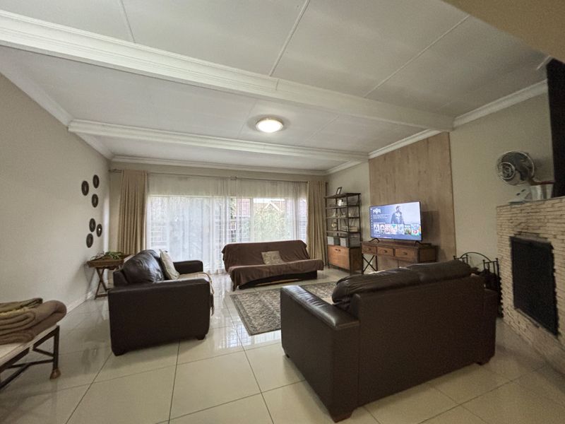 Spacious living room featuring tiled flooring, a brick fireplace, and large sliding glass doors providing natural light.