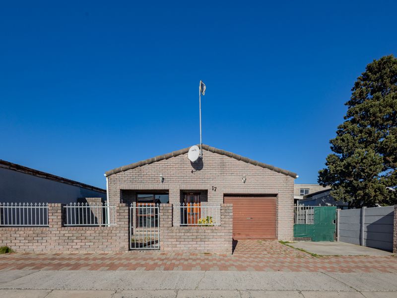 Front elevation of a single-story face brick house featuring a single garage, paved driveway, and secure boundary walling.
