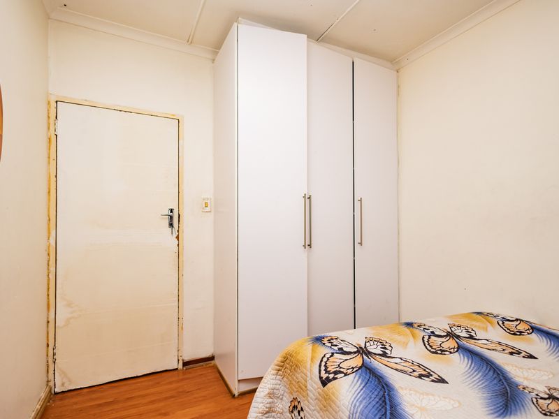 A bedroom featuring laminate flooring, a built-in white wardrobe, and coved ceiling detailing.