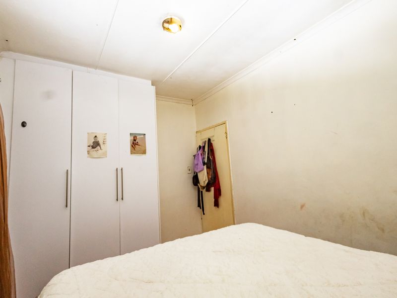 A bedroom featuring built-in cupboards and standard ceiling finishes, requiring cosmetic updates to the wall surfaces to improve the overall aesthetic.