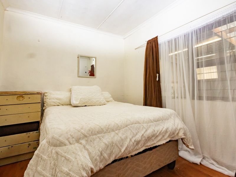 A bedroom featuring laminate flooring and a coved ceiling, requiring cosmetic updates to the wall and ceiling finishes to improve its overall condition.