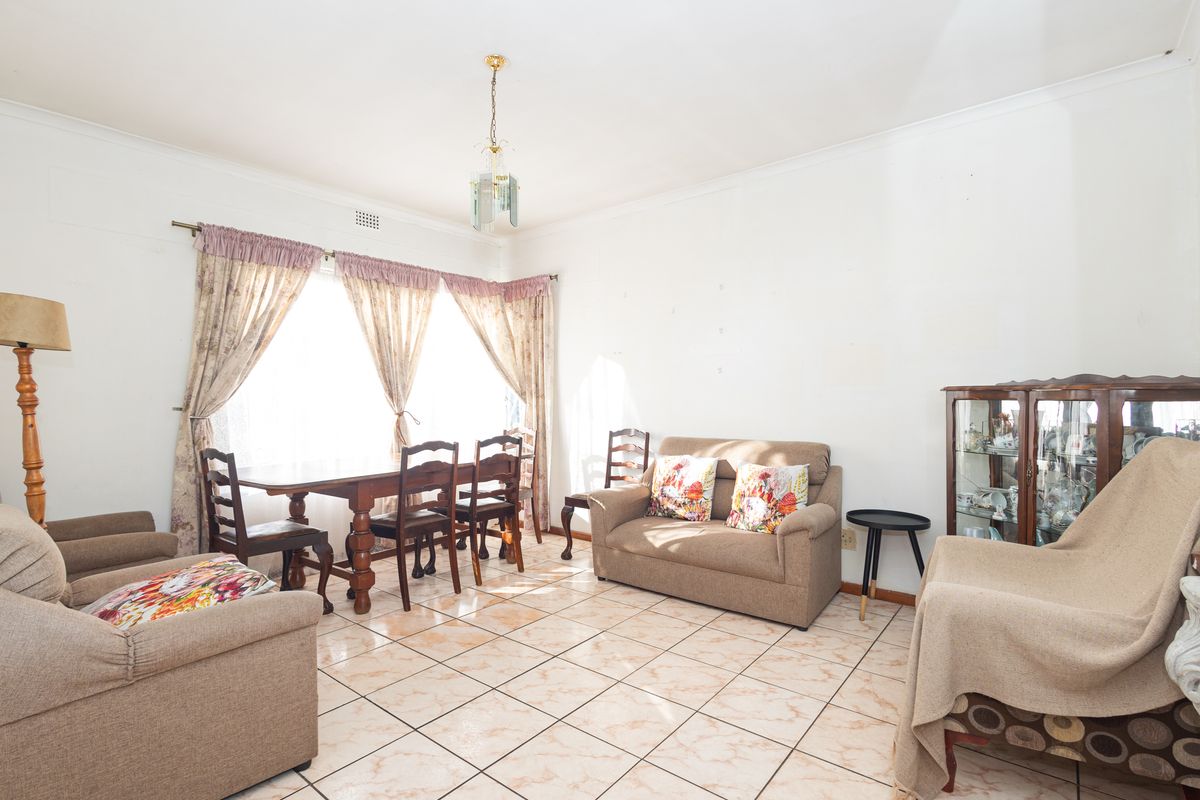 A living room featuring tiled flooring and a coved ceiling, offering a functional space with potential for cosmetic updates and modernization.