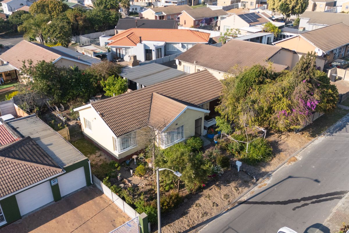 Aerial view of a residential property featuring a tiled roof, front garden, and detached garage within a suburban neighborhood setting.