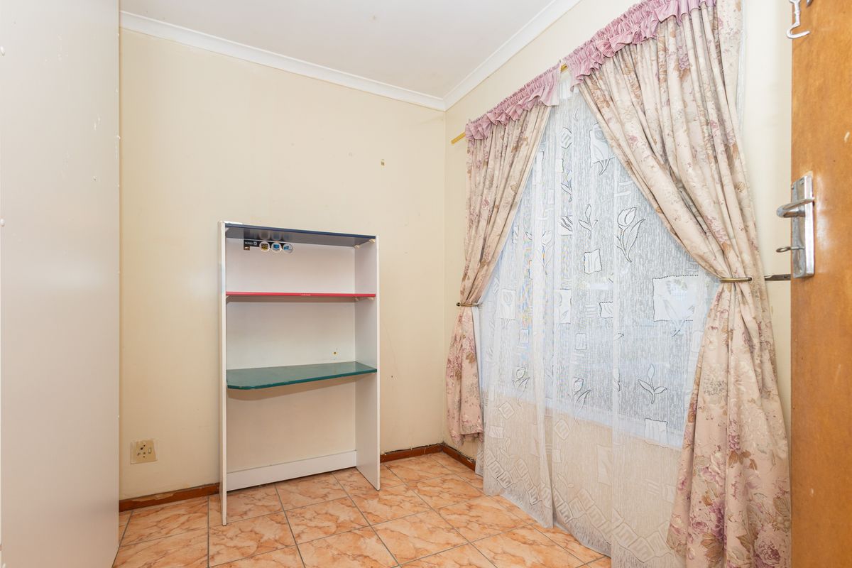 A compact bedroom featuring tiled flooring, a built-in cupboard, and coving, offering a blank canvas for renovation or restyling.