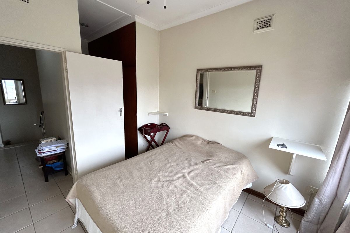 A functional bedroom featuring tiled flooring, a ceiling fan, and built-in storage, offering a neutral base for potential interior updates.