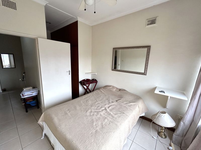 A functional bedroom featuring tiled flooring, a ceiling fan, and built-in storage, offering a neutral base for potential interior updates.