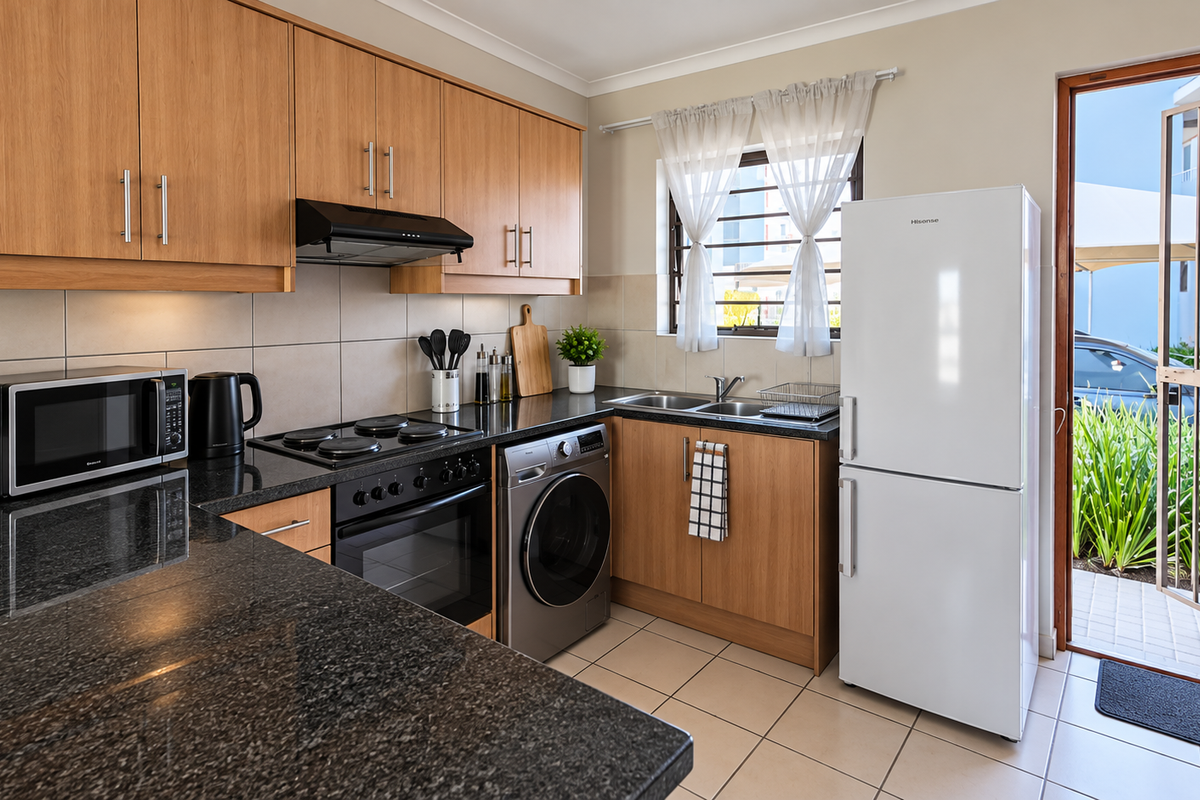 A well-maintained kitchen featuring wood-finish cabinetry, granite countertops, integrated appliances, and direct access to an outdoor area through a security gate.
