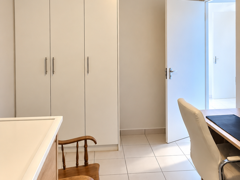 A well-maintained bedroom featuring neutral tiled flooring, built-in white cupboards, and a simple flush mount ceiling light fixture.