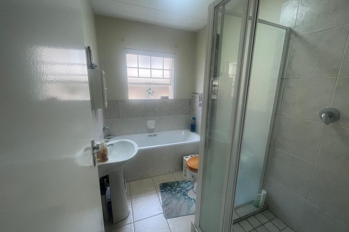 A functional bathroom featuring a pedestal basin, a built-in bathtub, and a separate shower enclosure with tiled finishes throughout.