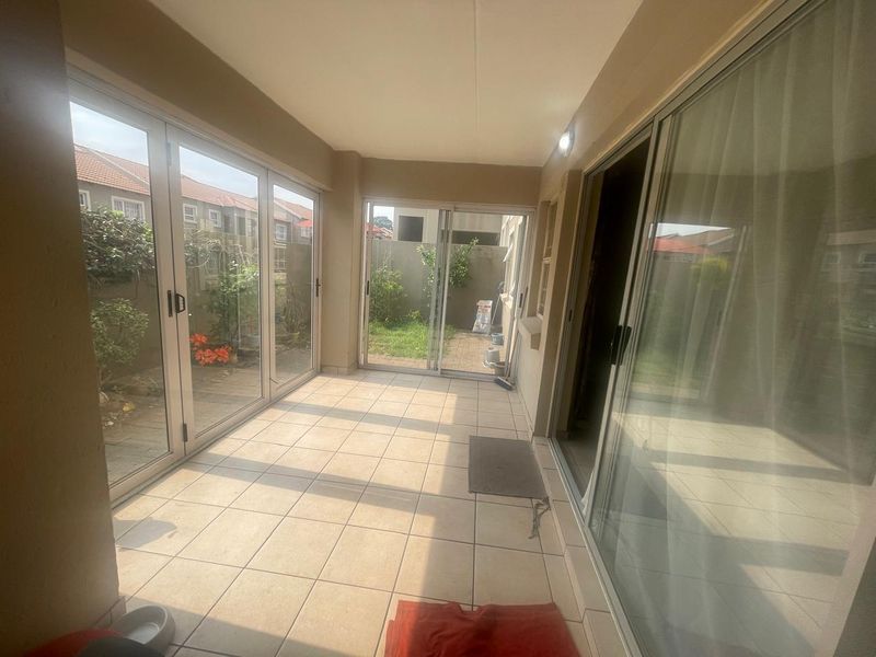 A bright, enclosed patio area featuring tiled flooring and extensive glass sliding and bi-fold doors providing direct access to the rear garden.