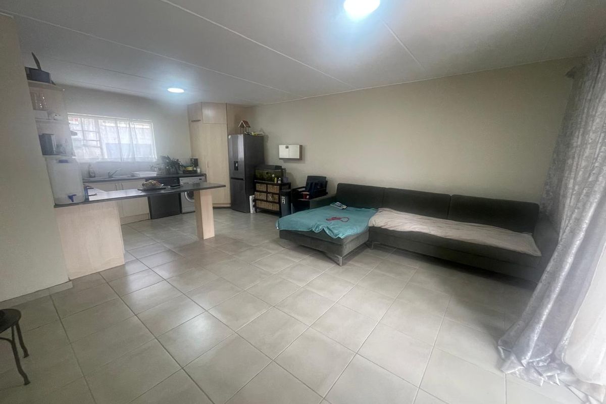 Open plan living area featuring a kitchen with breakfast bar and tiled flooring throughout, creating a functional and connected living space.