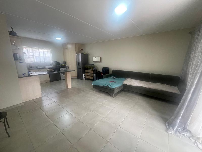 Open plan living area featuring a kitchen with breakfast bar and tiled flooring throughout, creating a functional and connected living space.