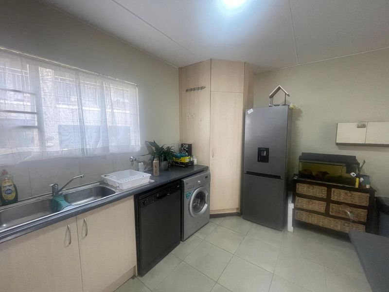 A functional kitchen featuring built-in cabinetry, laminate countertops, a stainless steel sink, and tiled flooring with space for integrated appliances.