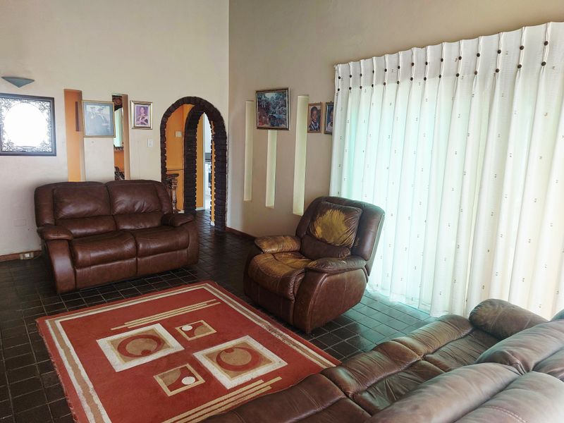 A living room featuring dark tiled flooring, an arched entryway, and recessed wall niches, with natural light provided by a large sliding glass door.