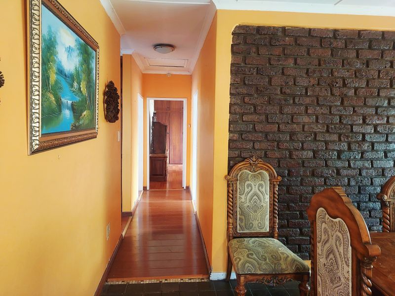 A hallway featuring hardwood flooring and a prominent exposed brick feature wall, leading towards the bedroom area.